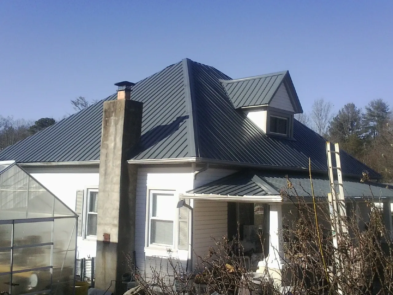 Dark blue standing seam metal roof on a white farmhouse with dormer — Slate & Tile Roof Repair by Roofing Brothers in The Plains