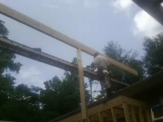 Carpenter setting a ridge beam over a new addition frame — Ice Dam Removal by Roofing Brothers in The Plains