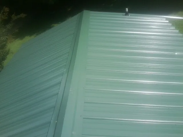 New green metal panels meeting at the ridge of a roof — Flat Roof Repair work by our crew in The Plains