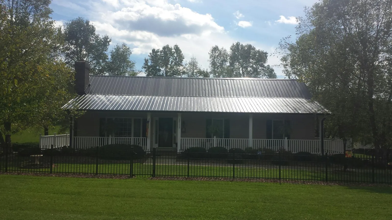 Gray metal roof on a brick ranch with a full width front porch — Gutter Guard Installation work by our crew in The Plains