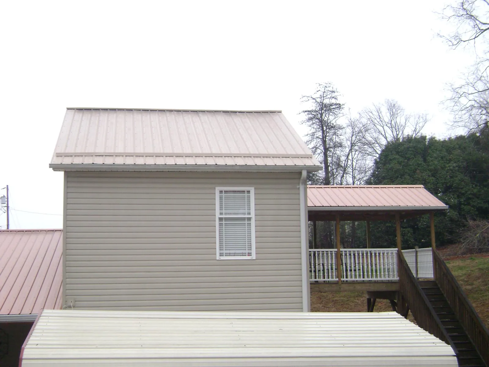 Tan metal roofs on a two story addition and attached porch, from a Roof Replacement job in The Plains
